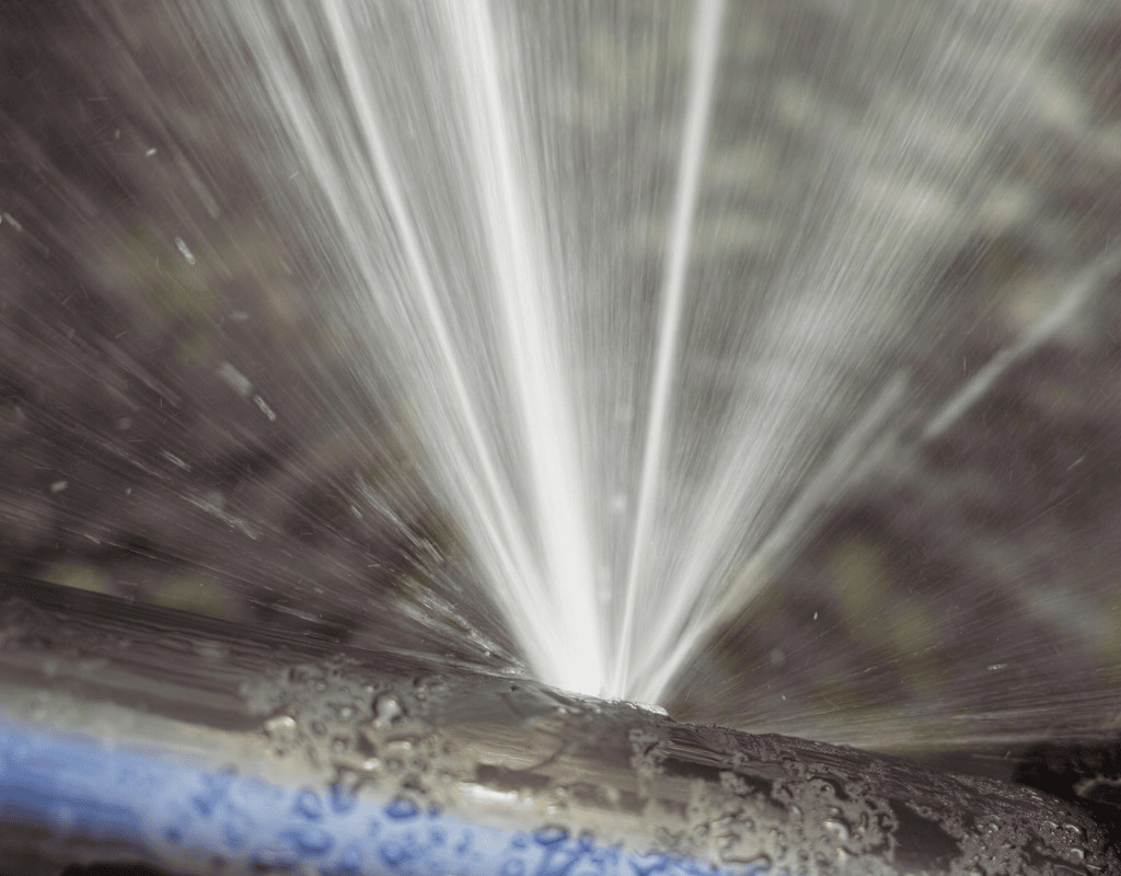 Close-up of water spurting from a leaky irrigation pipe