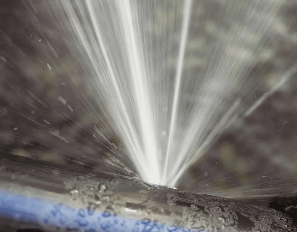 Close-up of water spurting from a leaky irrigation pipe