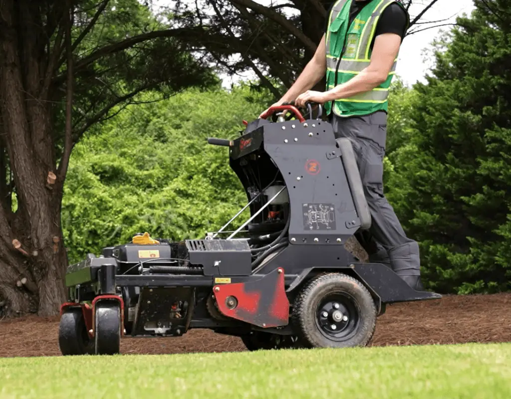Technician operating a core-aerator machine on a lush green lawn