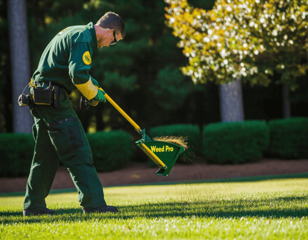 WeedPro technician broadcasting seed and soil repair mix on a thin spot in an Atlanta, GA lawn for the Lawn Repair Program.