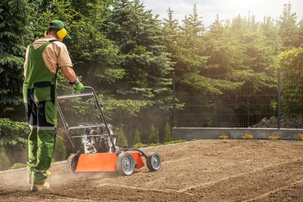 Man using a lawn aerator on a dirt lawn surrounded by greenery, illustrating aeration and seeding techniques for lawn revival in Atlanta.