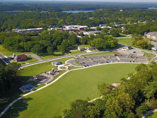 Aerial view of a lush green park in Acworth, GA, featuring open grassy areas, tree-lined paths, and surrounding residential buildings, emphasizing healthy landscapes and community spaces.