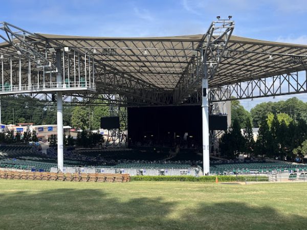 Outdoor concert venue with a large covered stage and empty seating area, surrounded by greenery, located in Alpharetta, GA, reflecting vibrant community events.