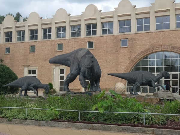 Dinosaurs sculptures in a landscaped area outside a building, representing prehistoric life and attracting visitors in DeKalb County, GA.