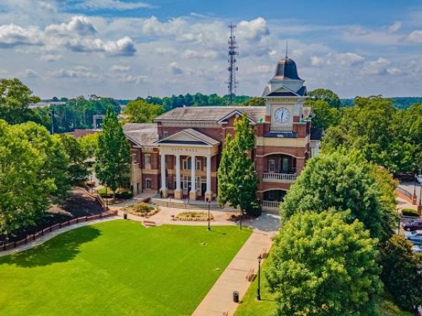 Aerial view of a historic building with a clock tower, surrounded by green lawns and trees in Duluth, GA, highlighting the vibrant community and outdoor spaces.