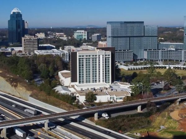 Aerial view of Dunwoody, GA, showcasing modern buildings, a highway, and lush greenery, emphasizing the urban landscape and community environment relevant to Weed Pro Lawn Care services.