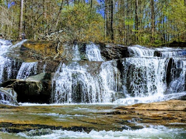 Waterfall cascading over rocks in a forested area, showcasing natural beauty and tranquility, relevant to outdoor aesthetics in Cherokee County, GA.