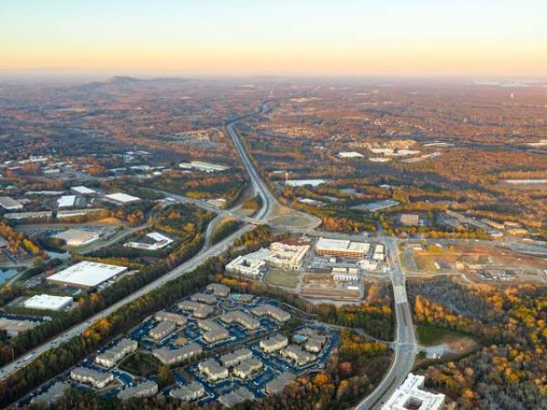 Aerial view of Johns Creek, GA, showcasing residential areas, commercial buildings, and surrounding landscapes, highlighting the community's appeal and proximity to nature.