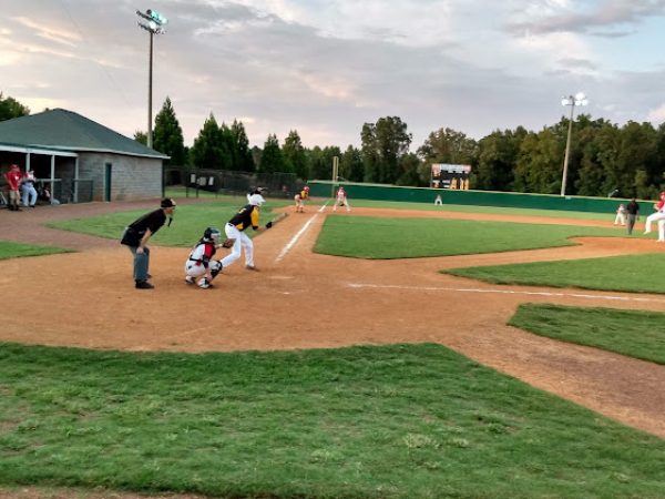 Baseball game in progress on a well-maintained field in Loganville, GA, featuring players in action, a catcher in position, and a dugout area, emphasizing local sports engagement and community activities.