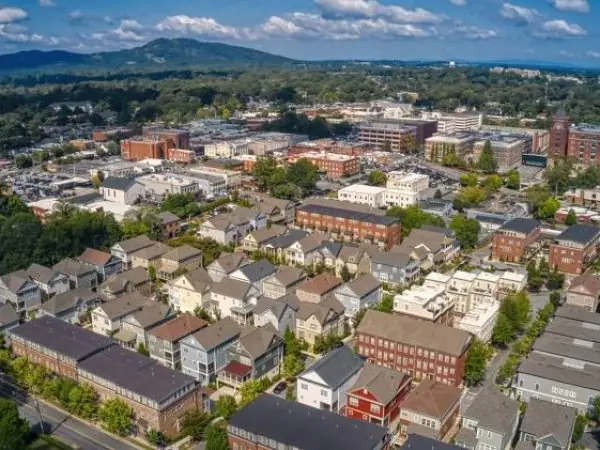 Aerial view of Marietta, GA, showcasing residential neighborhoods and commercial areas with lush greenery and a backdrop of rolling hills, emphasizing the community’s appeal and outdoor spaces.