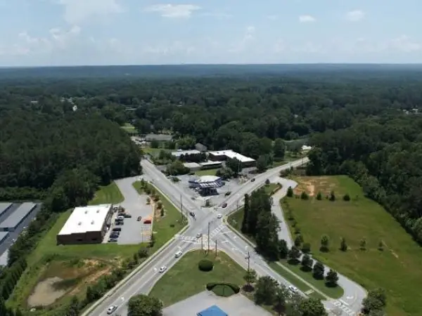 Aerial view of a suburban intersection in Powder Springs, GA, showcasing lush greenery, commercial buildings, and well-maintained roads, emphasizing the community's appeal for professional lawn care services.