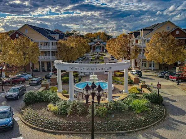 Smyrna Market Village in Cobb County, GA, featuring a central fountain, landscaped gardens, and surrounding shops, emphasizing community and curb appeal.
