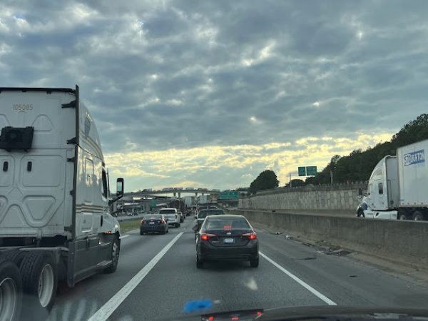 Traffic on a busy highway in DeKalb County, GA, with trucks and cars under a cloudy sky, illustrating the area's commuting landscape.