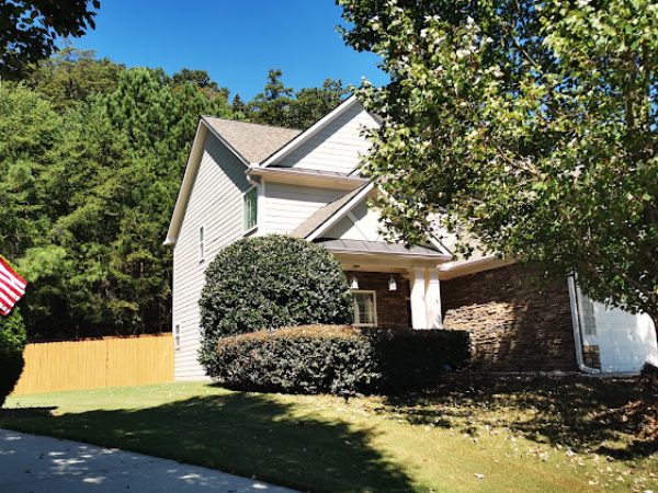 Residential home in Cherokee County, GA, showcasing well-maintained lawn, vibrant greenery, and American flag, illustrating the enhanced curb appeal and property value emphasized by Weed Pro Lawn Care services.